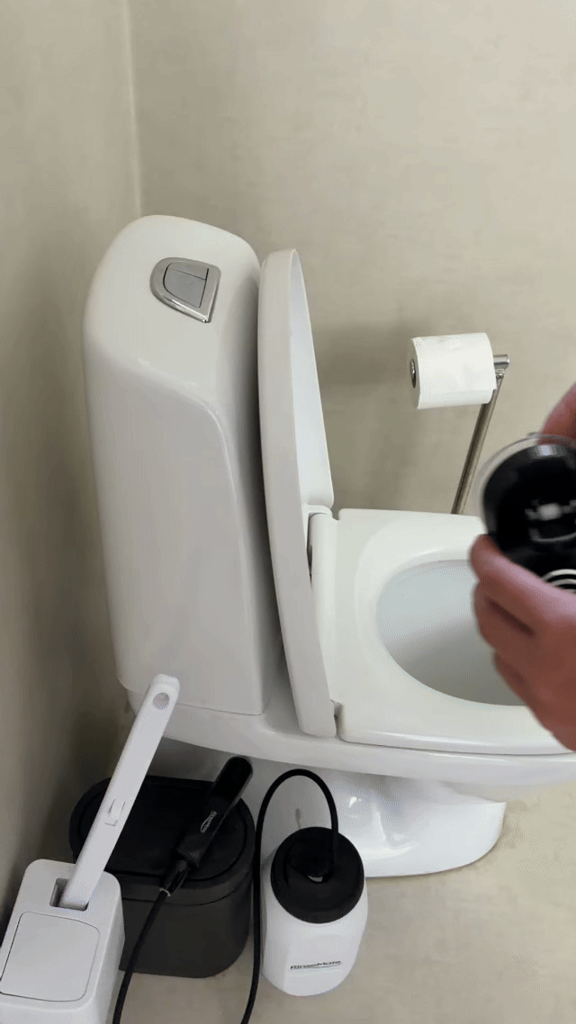 Hand attaching the RinseMate holder to the side of a toilet in seconds.